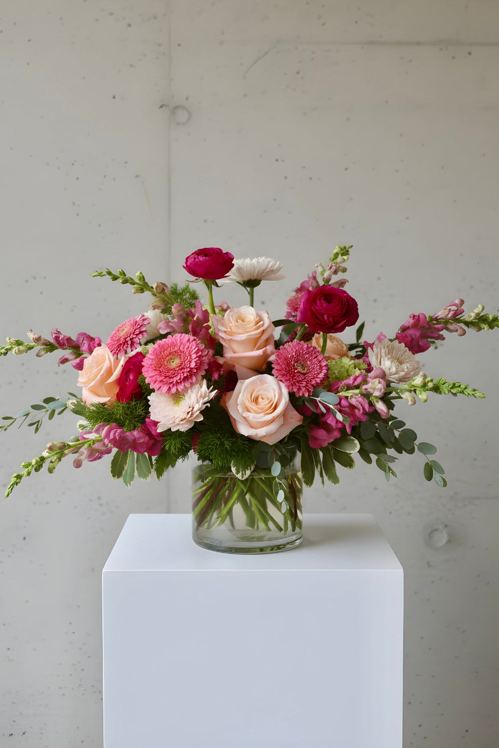 Shades of pink flowers like roses, snapdragons, stock and ranunculus with pretty greenery designed in a vase