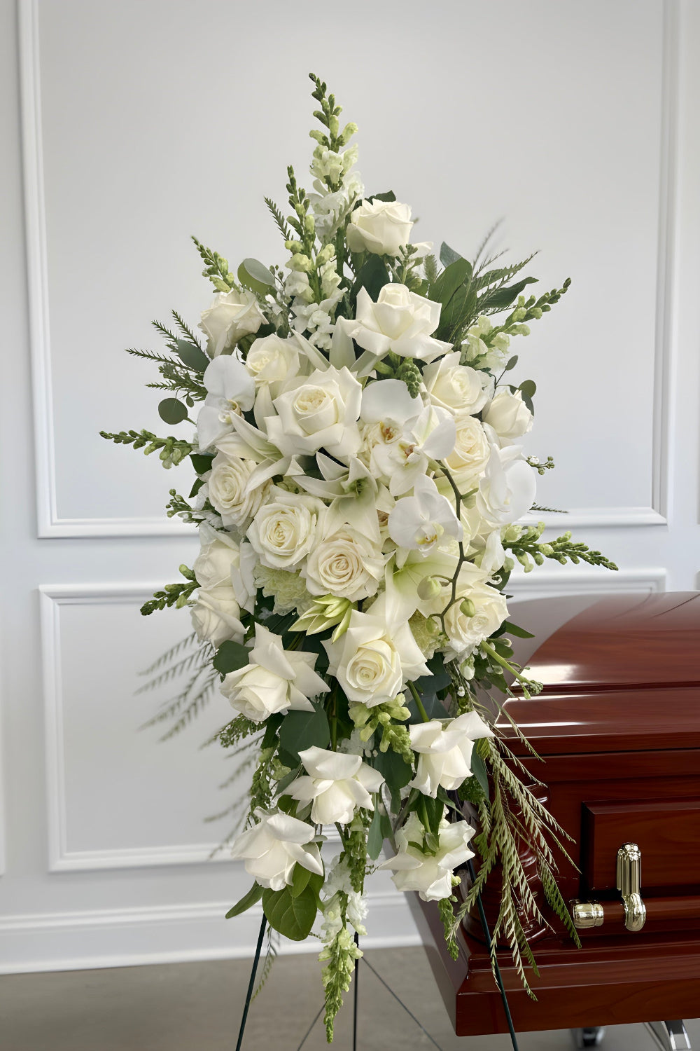 very full lush all white standing funeral memorial flower spray full of roses, orchids, snapdragons, lilies and premium greenery