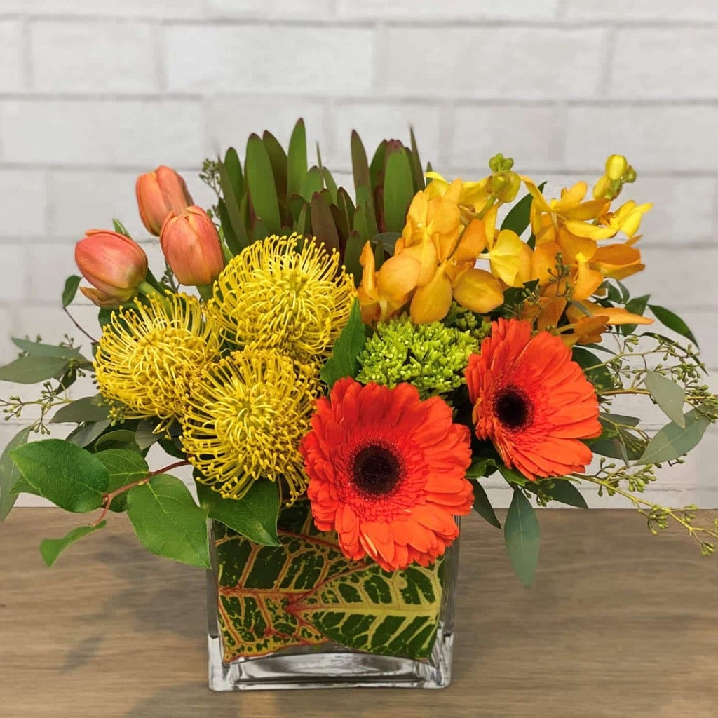 protea, orchids, tulips, gerbera daisies, leaf wrapped vase